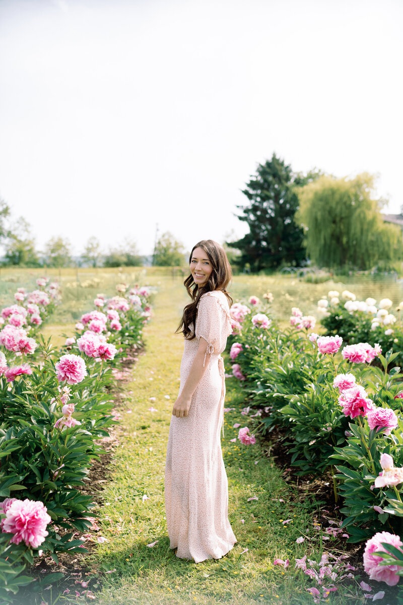Seattle area family photographer posing for a photo with her daughter wearing a long doen dress in a field of flowers. 