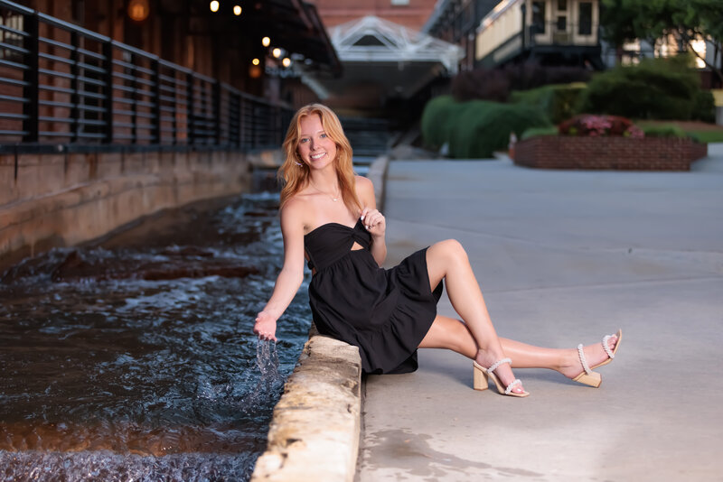 Durham Senior Portraits by the water wearing a black dress.