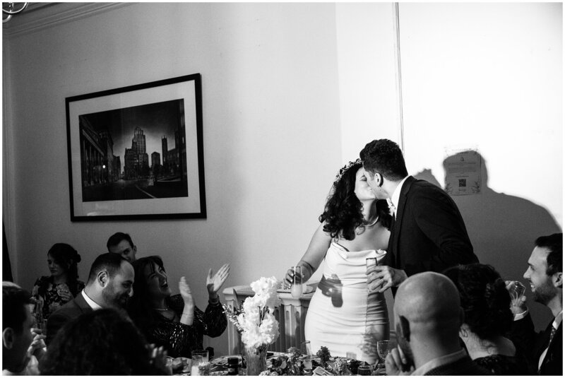 Couple kissing in front of wedding guests clapping