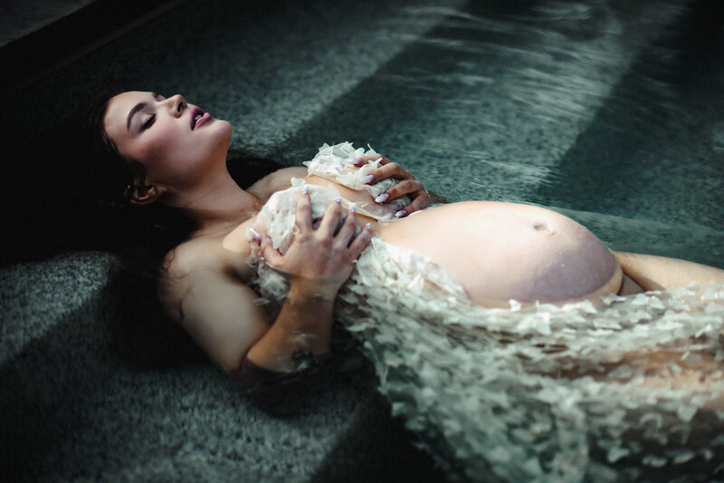 Pregnant mother laying on pool steps at the urban farmhouse in Boise Idaho with eyes closed wrapped in a white butterfly dress
