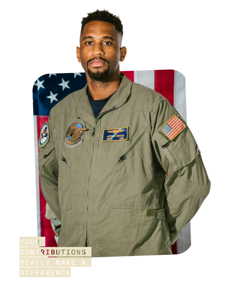 man in army uniform standing in front of an american flag with hands behind his back
