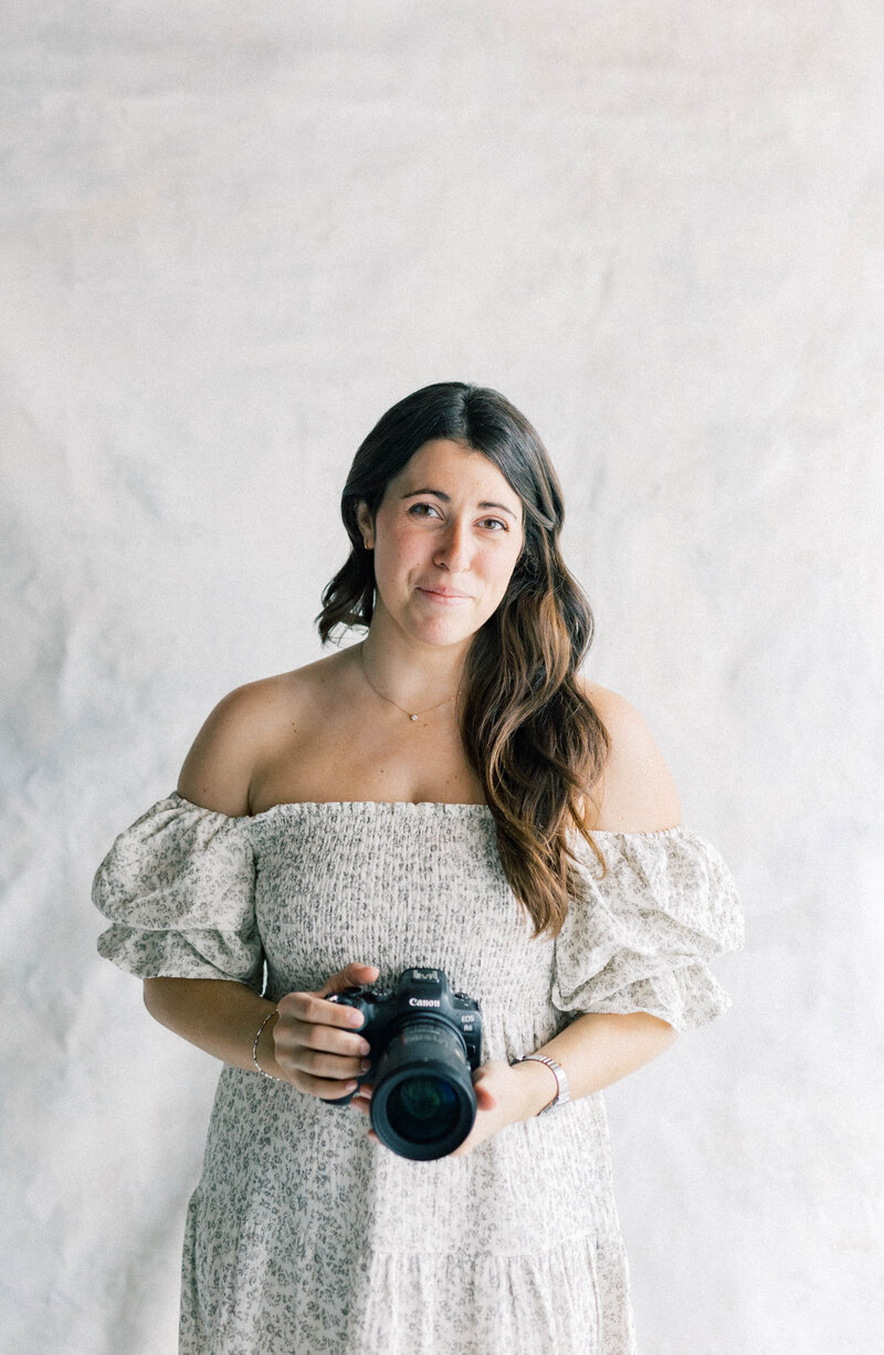 knoxville photographer in white and gray dress holding canon camera smiling at the camera