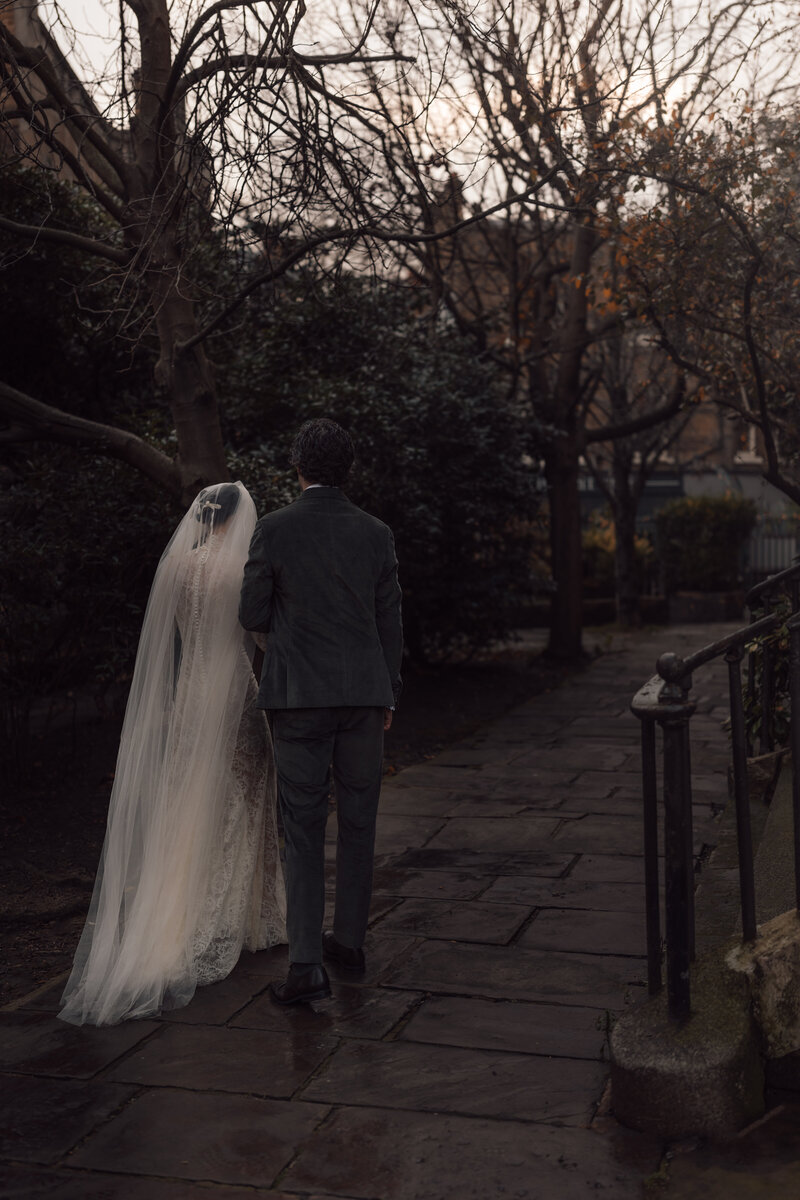 married couple take a moment of silence to walk hand in hand during their golden hour wedding shoot in central london