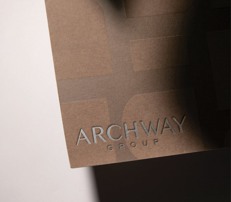 Archway Group logo embossed on a textured brown surface, featuring a sleek and modern brand identity with metallic lettering.