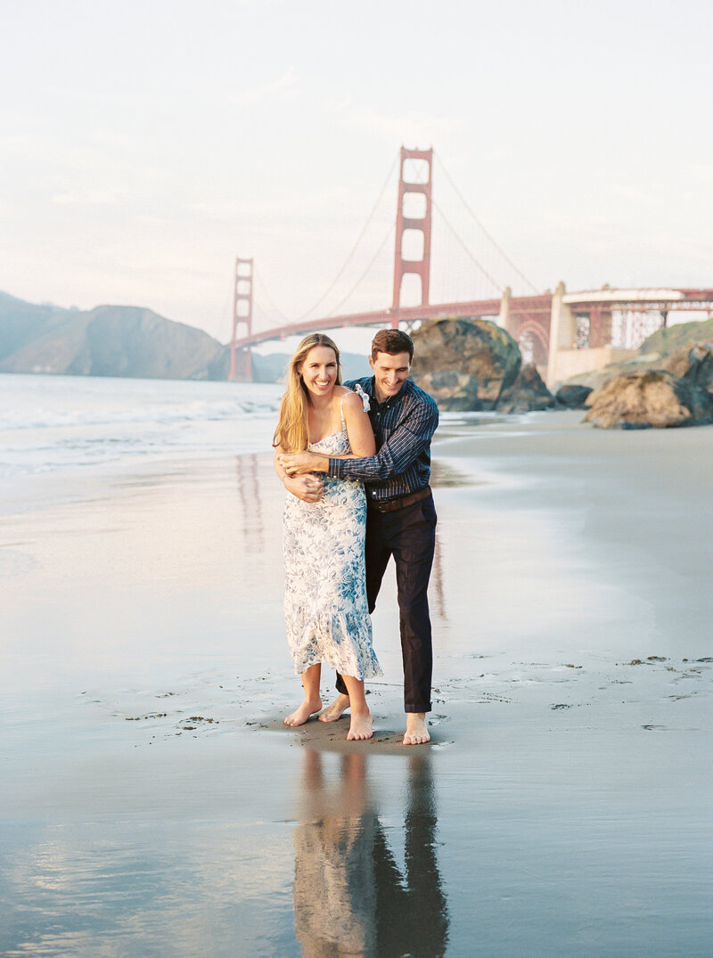 Couple embracing and hugging by the water and golden gate bridge