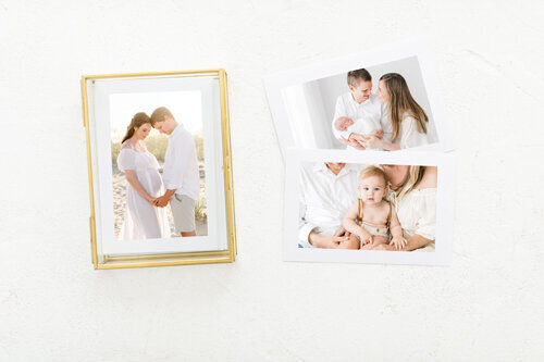 Framed maternity photo taken on the beach in Destin, alongside printed newborn and baby portraits by a Destin maternity photographer specializing in heirloom artwork.
