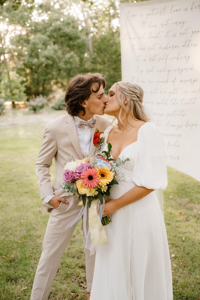 Bride and groom walk hand in hand while groom holds brides bouquet. They admire each other while Shelly Voss captures the moment.