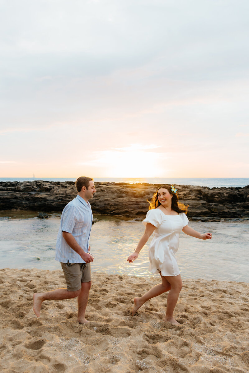 True-to-color candid photo of a couple running at Paradise Beach Cove on Oahu