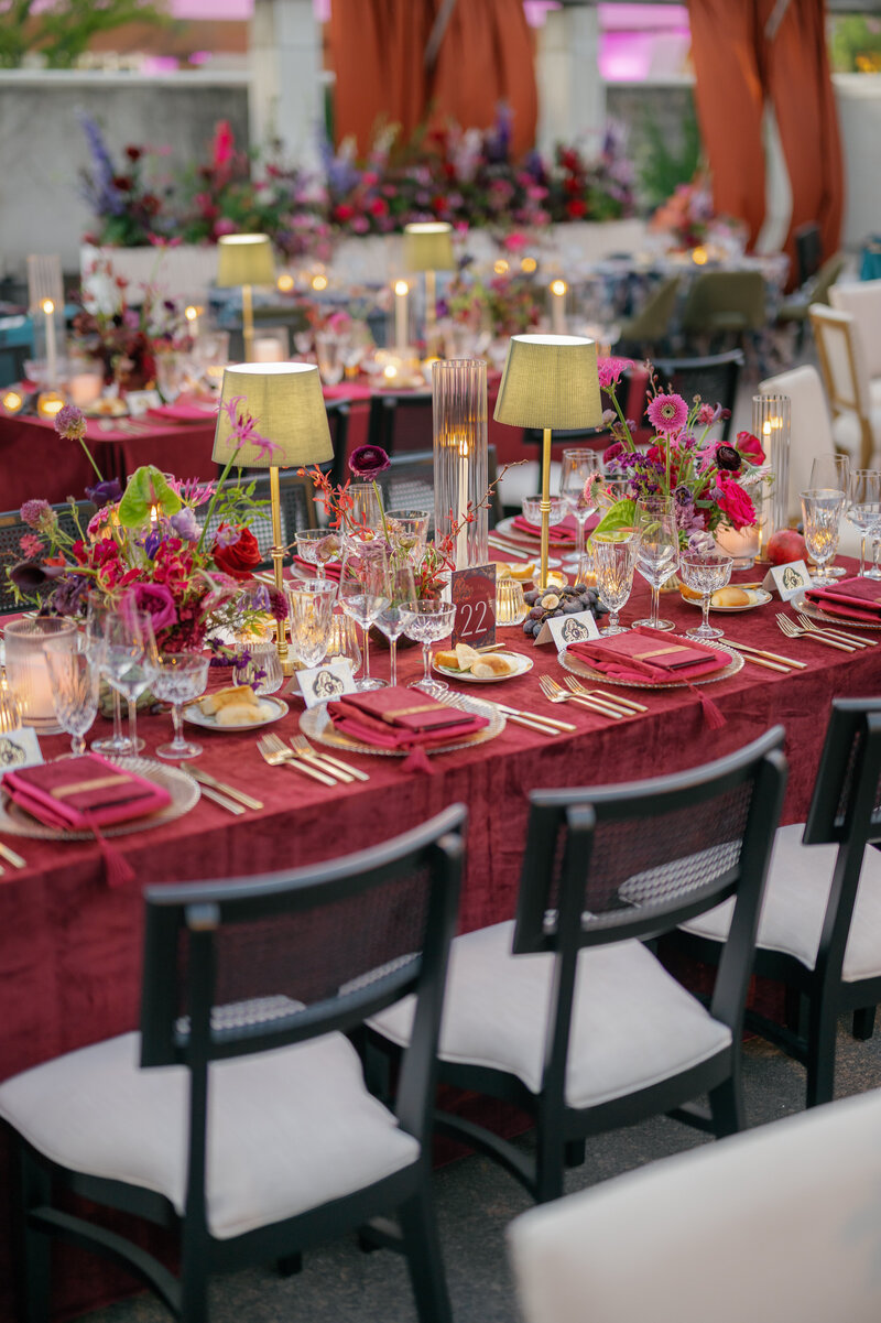 Table setting with floral arrangements, blue tablecloth, chandelier.