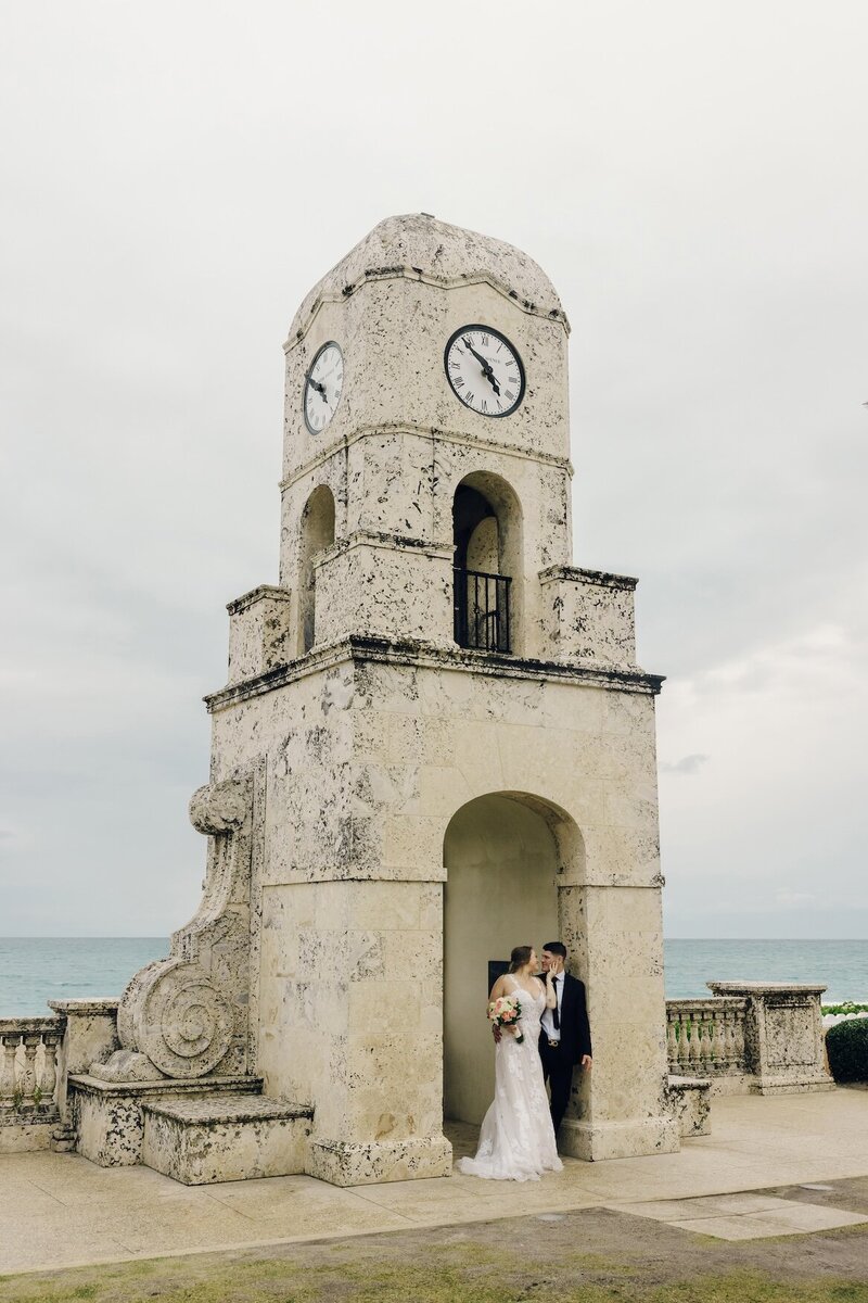 bride and groom share a kiss in front of the ocean