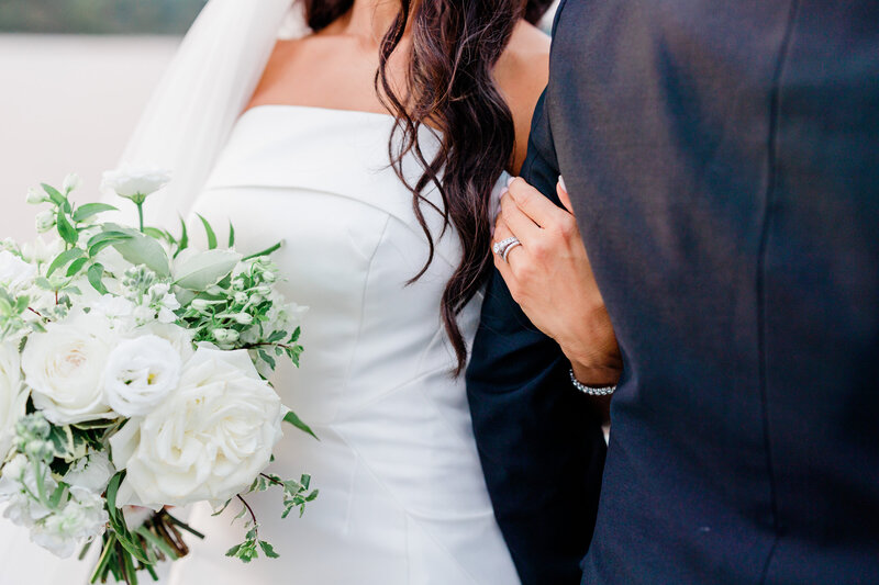 bride holding groom arm and white bouquet