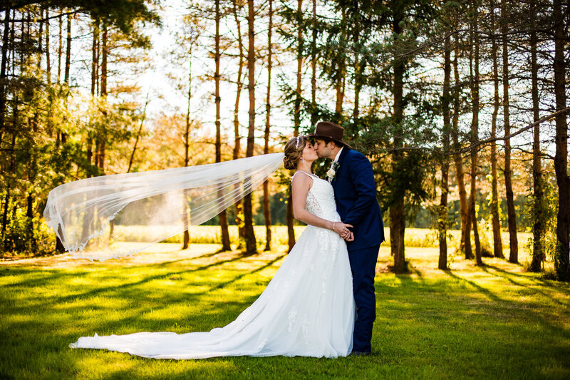 Bride and groom smiling at each other under an umbrella in front of Perry Monument on Presque Isle State Park in Erie, PA