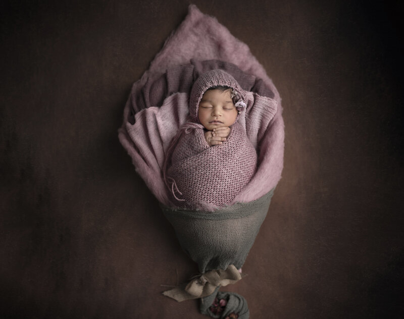 "Sleeping newborn nestled inside a delicate flower prop, surrounded by soft petals, captured in a dreamy, floral-inspired fine art newborn photography session in Ottawa."