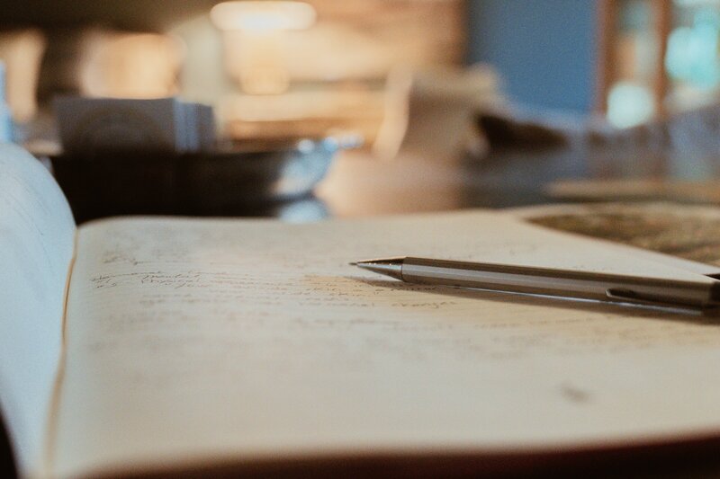 Filled notebook with clicker pencil on desk with silver bowl holding business cards