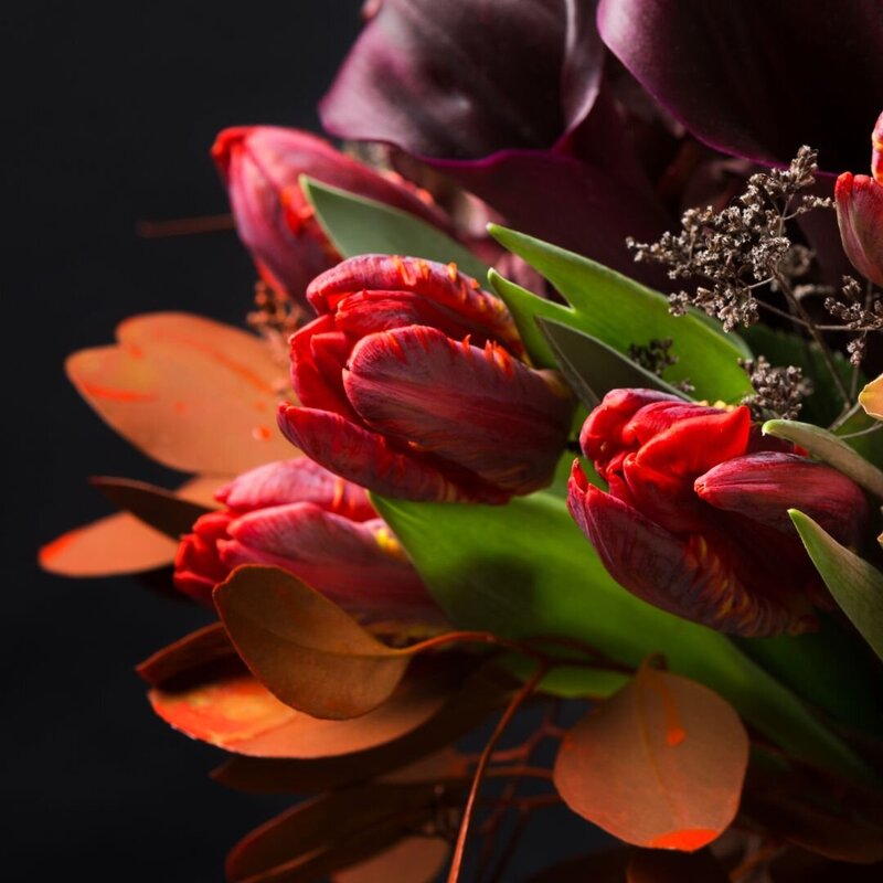 Moody fall flowers in plum, burgundy and orange with greenery on a black background by Elevations Design Co. | Florist in Azle Texas