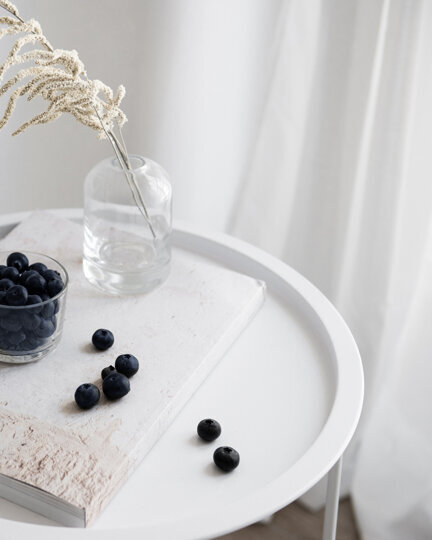 round whit table with blueberries, flowers and a white book