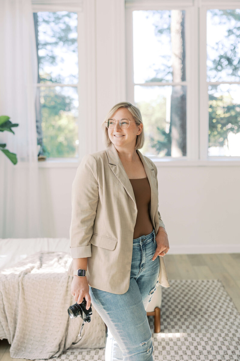 Woman holding camera posing in brightly lit room