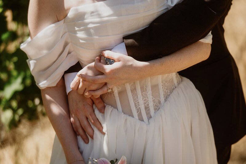 Couple tenderly holding hands during their summer vineyard adventure elopement portraits