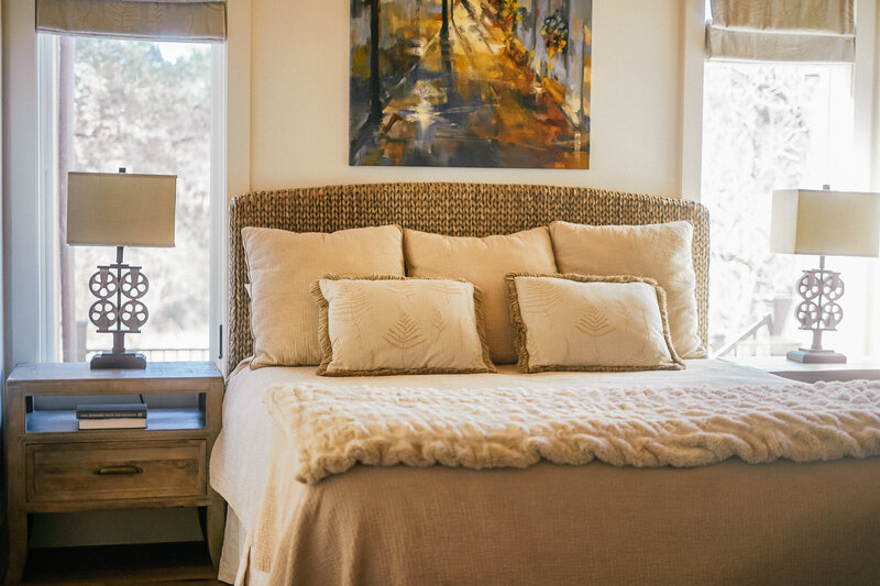 Bed with woven headboard and beige pillows and blankets