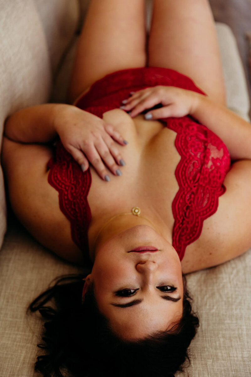 pretty lady in red lace lingerie laying on her back and glancing up as she looks fierce