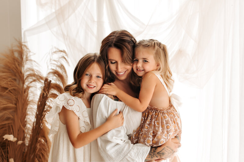 mom and two little girls photo in a studio snuggling 
