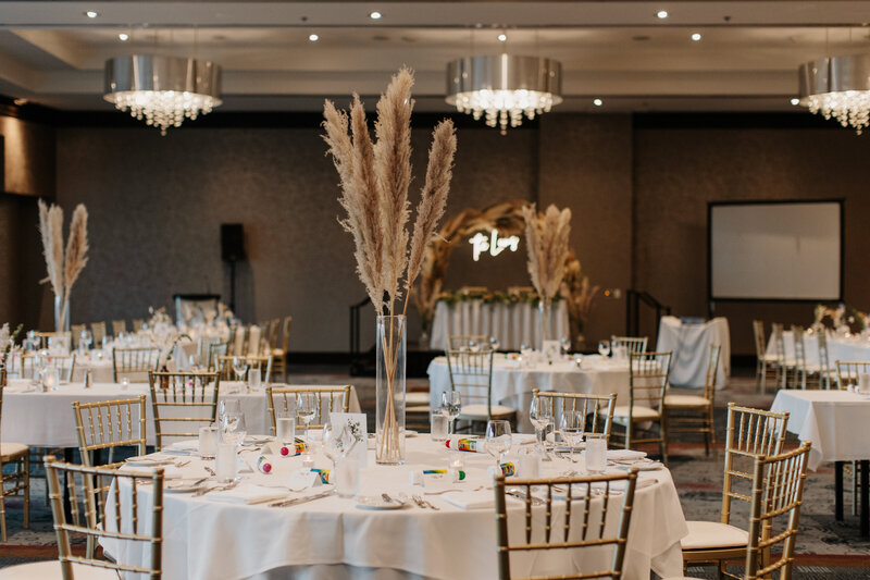 Hotel Ballroom feature tall pampas grass stems and round banquet tables.