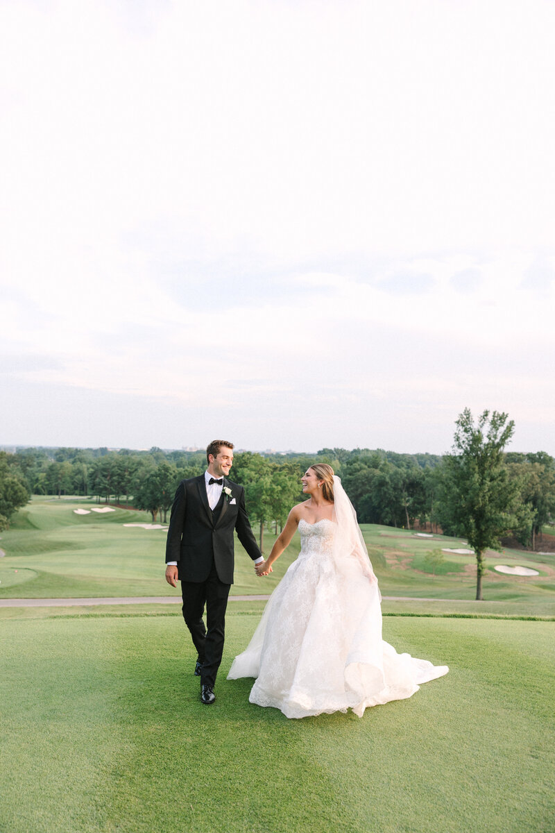 Bride in an elegant wedding dress kisses groom at sunset on the picturesque grounds of Evansville Country Club
