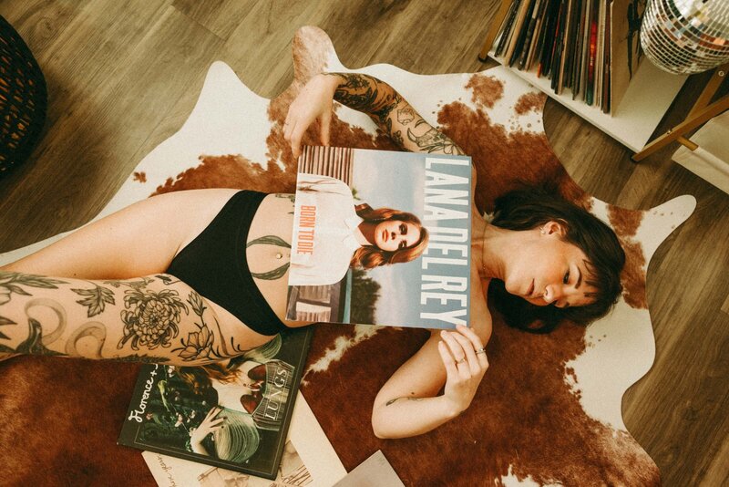 Tattooed Woman Lying on Cowhide Rug With Lana Del Rey Vinyl