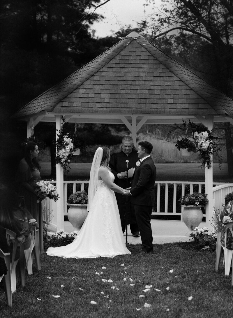 The bride and groom are standing near the altar, looking at each other and holding hands