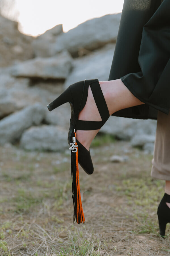 Close up of a senior's black high heel. The shoe has her 2025 senior tassel hanging on it.