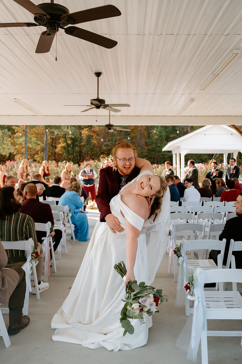 Groom dipping bride at ceremony aisle