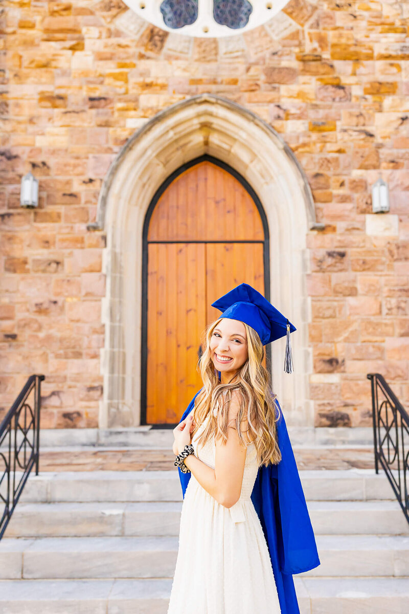 A senior girl with her cap and gown on a church doorstep