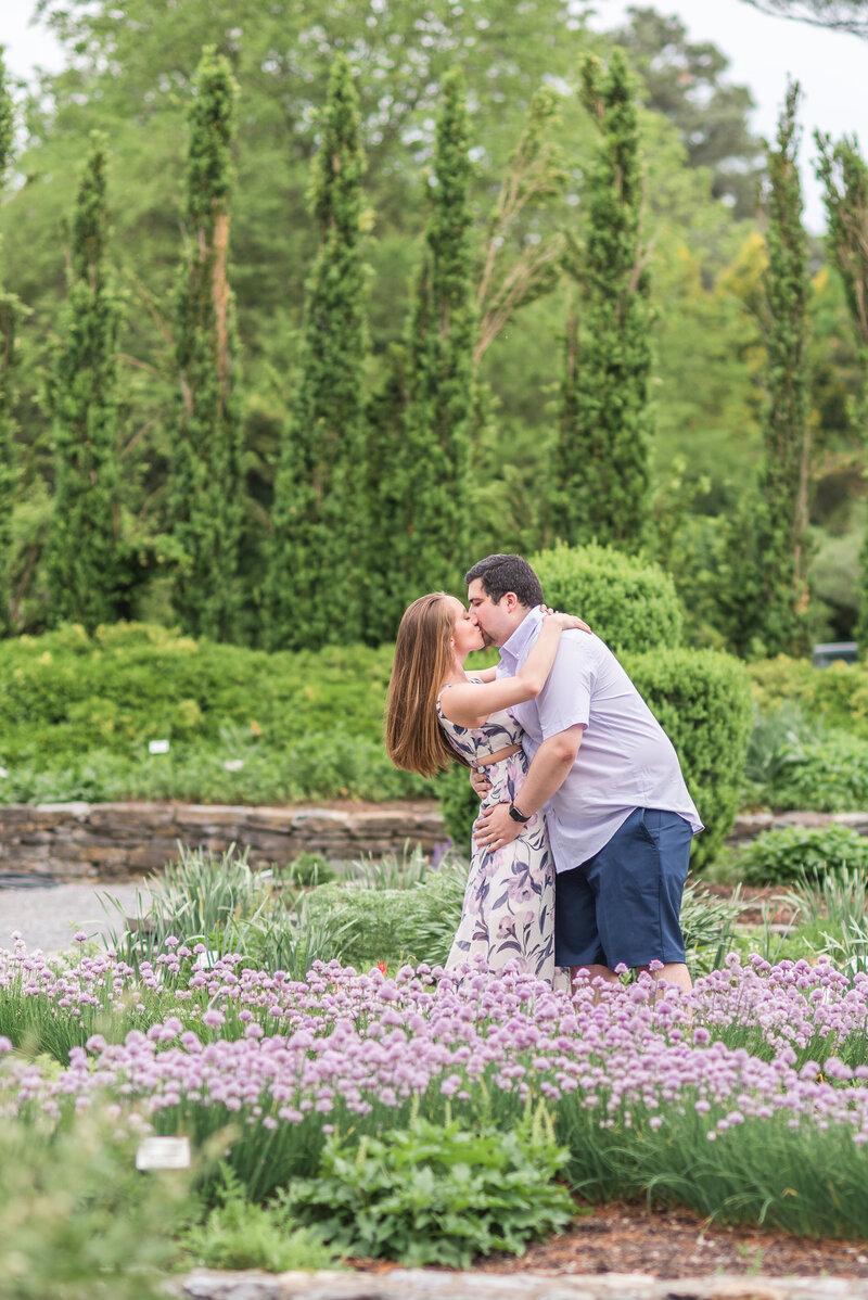 Couple embracing in a garden setting with purple flowers - Austin  TX based Wedding Photographer Lydia Teague