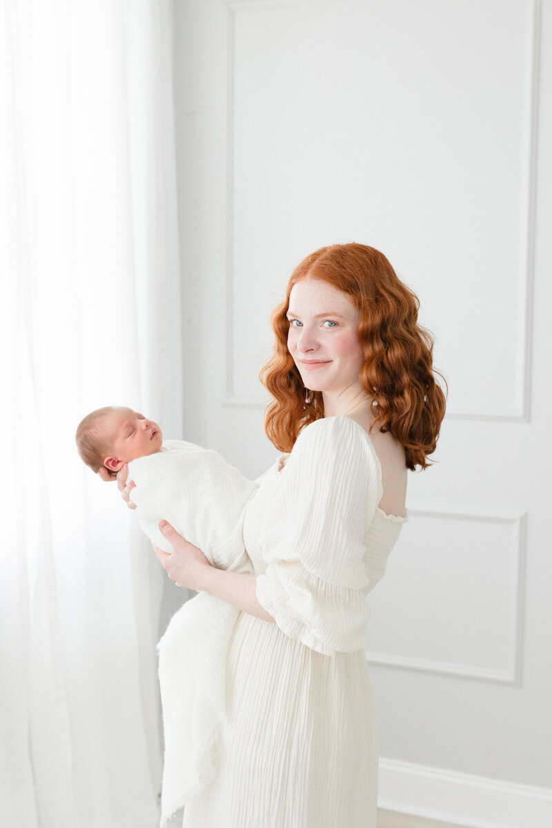 Portrait of a new mom wearing a cream nothing fits but dress while holding her sleeping newborn baby taken by northern kentucky newborn photographer missy marshall