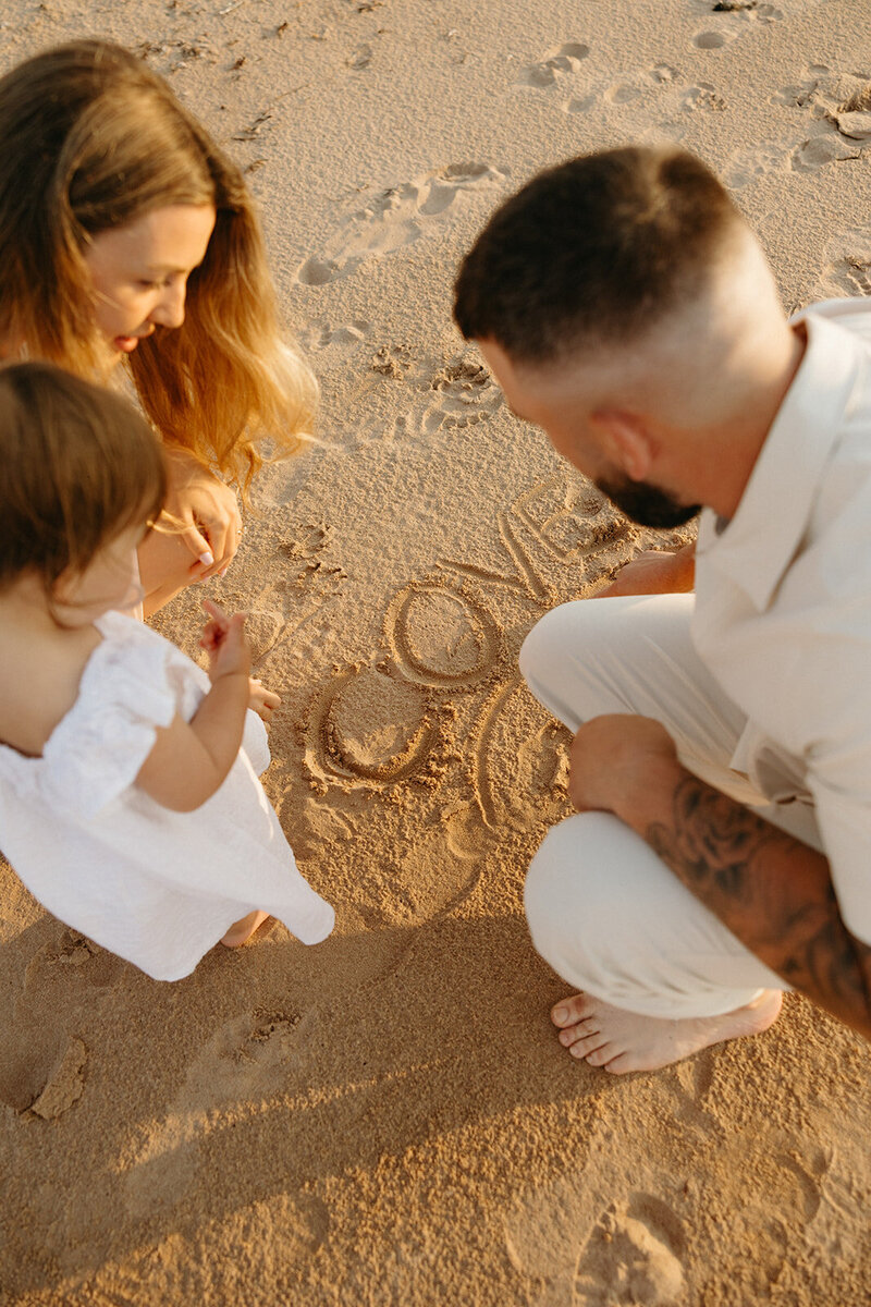 mom and dad holding baby on beach during lifestyle photos in pei