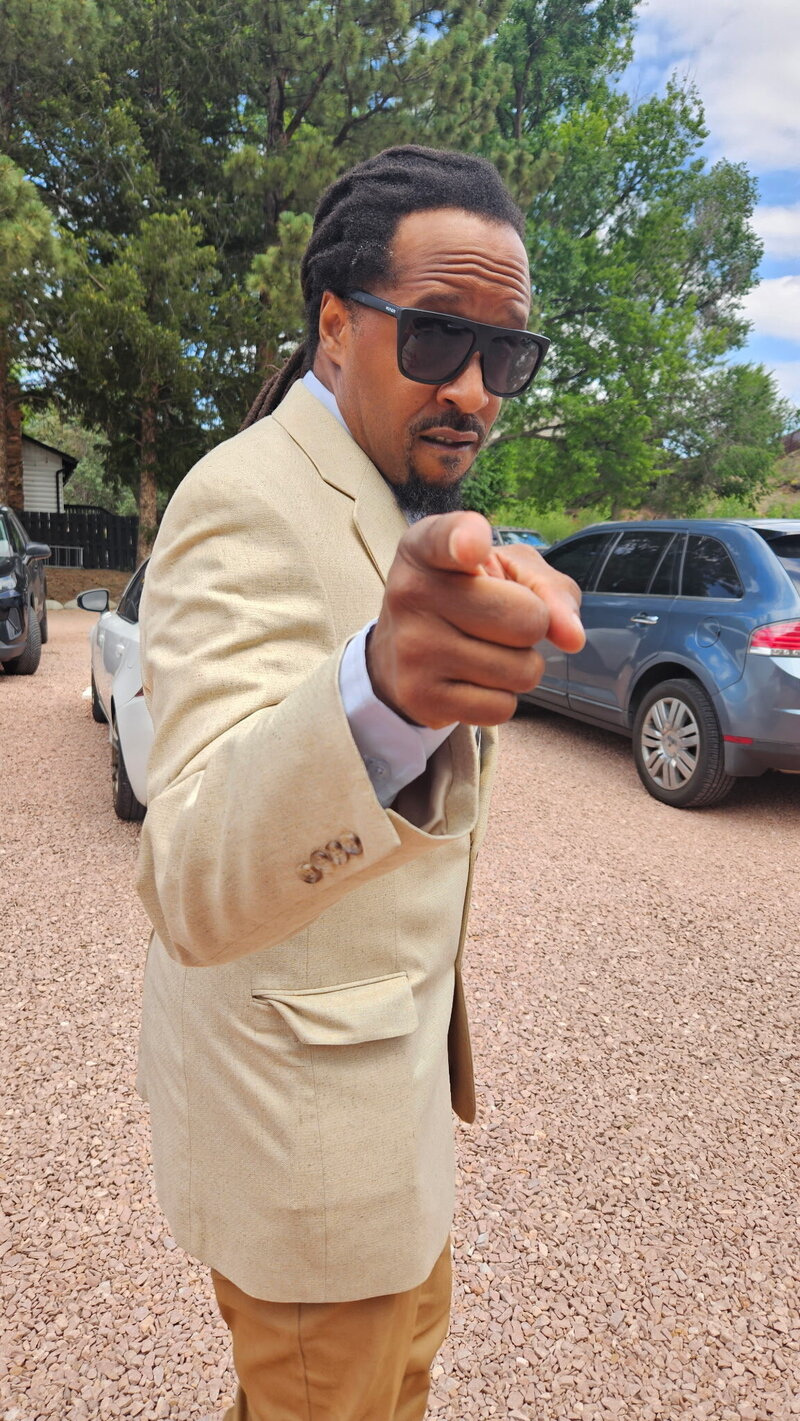 Founder Ijah in blazer ands sunglasses pointing direct. 