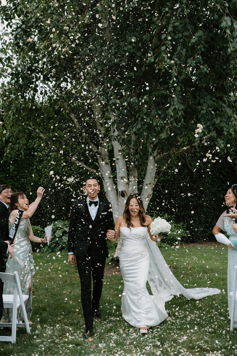 A couple walks under thrown flower petals at their Washington wedding. 