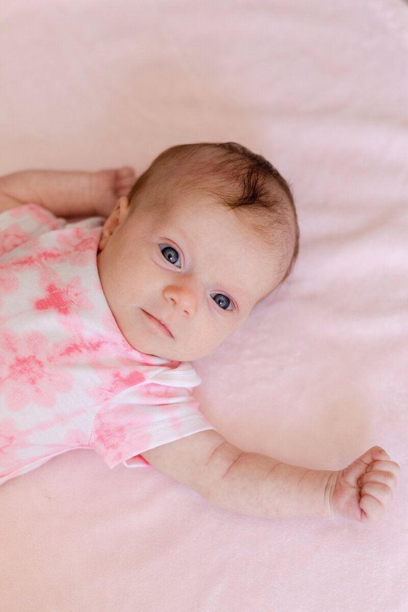 newborn poses naturally on pink blanket