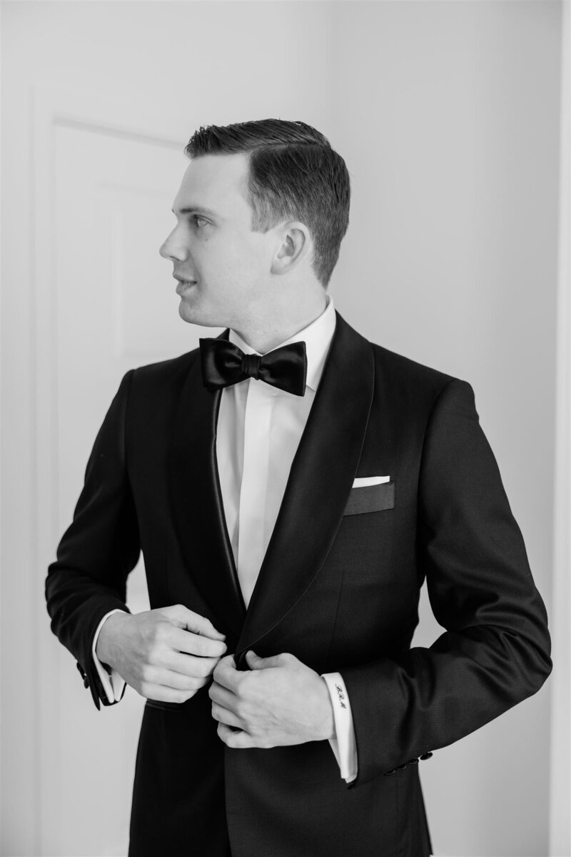 The groom looking away in a black and white portrait looking away at the Alfond Inn.
