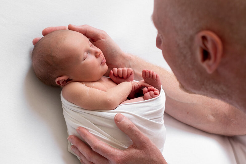 Een pure en liefdevolle foto van pasgeboren baby samen met grote zus. Perfect vastgelegd tijdens een newborn shoot aan huis.