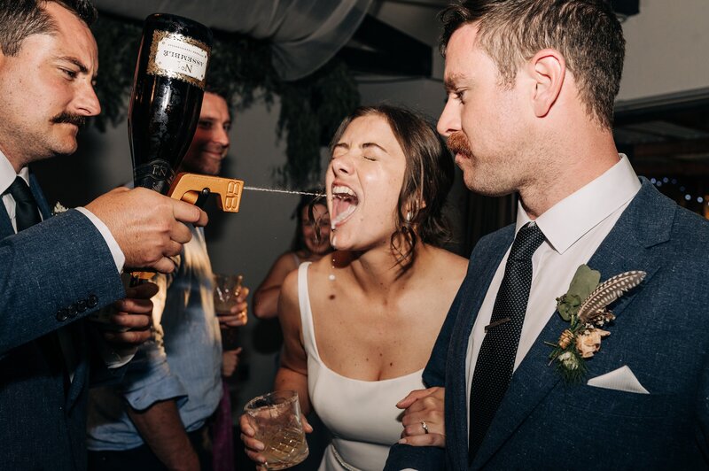 bride has champagne shot into mouth at akaroa wedding