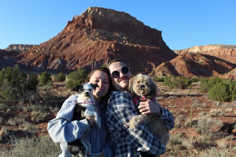 Molly, owner of Molly's Littlest Pet Salon in Waxahachie, Texas, smiling with her fiancé while holding their two beloved dogs