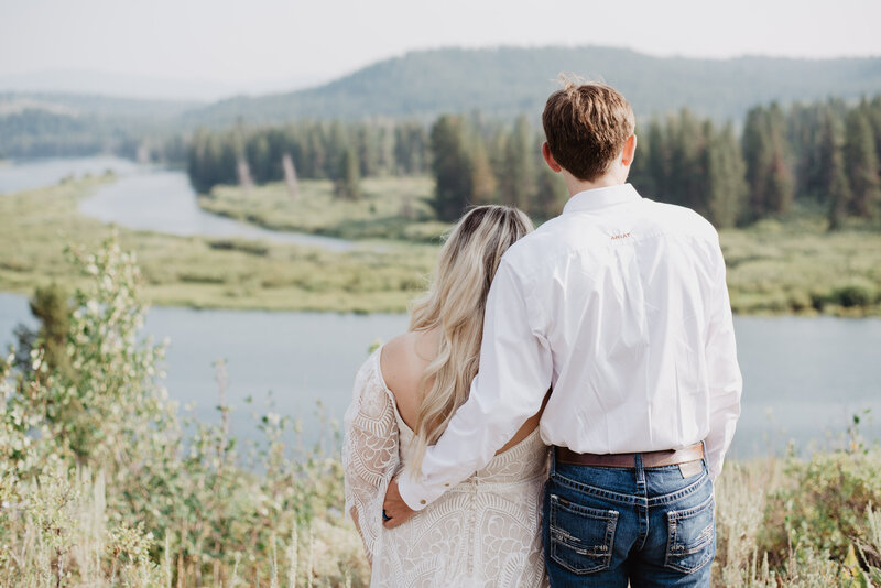 jackson hole wedding with bride and groom looking over the Snake river and the woods that surround it in the tetons for their jackson hole wedding  photos