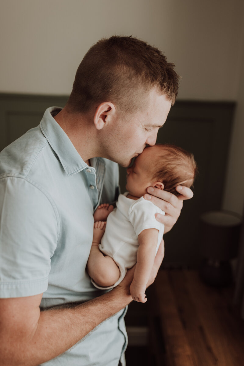 Dad kissing newborn baby