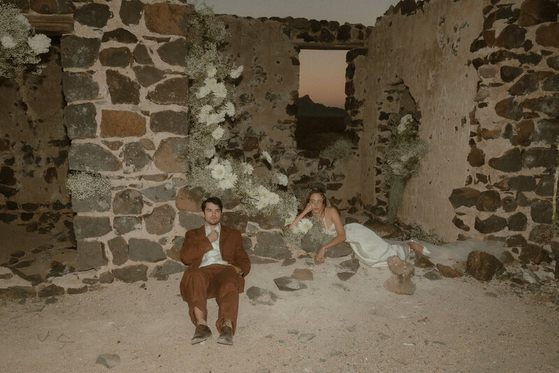 bride and groom posing among the ancient stone ruins in arizona at their elopement
