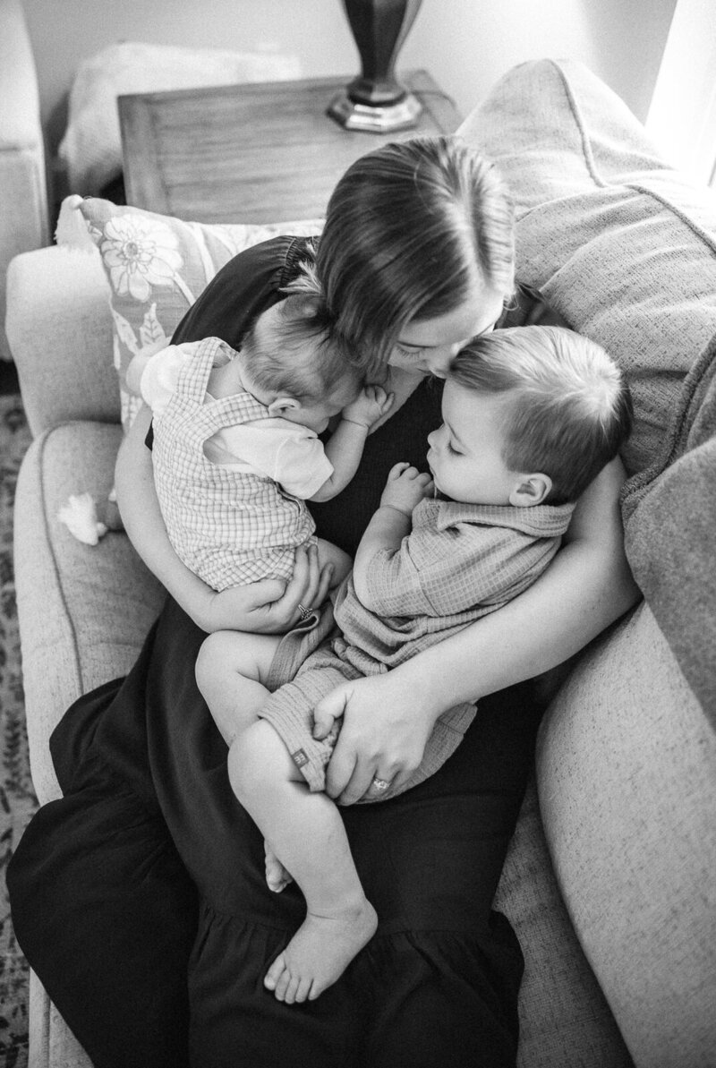 A black and white emotive image of a mother cuddling with her toddler and newborn son in Farmington, Missouri. 