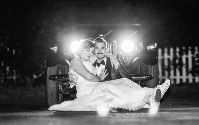 Bride and groom portraits in front of antique car at night