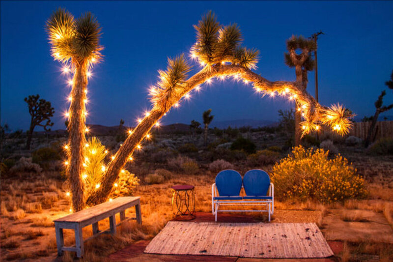 Branding Image Gatos Trail Studio Joshua Tree wrapped in white lights above love seat on small stage outdoors