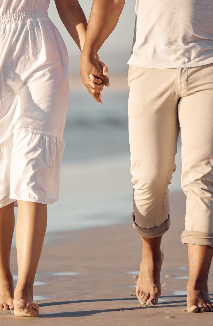 A loving couple walking on the beach representing the restoring of their relationship after infidelity. Couples in the aftermath of infidelity can benefit from The Affair Recovery Online Program: It's Okay to Stay by Relationship Experts in the Untied States, Canada and the rest of the world/.