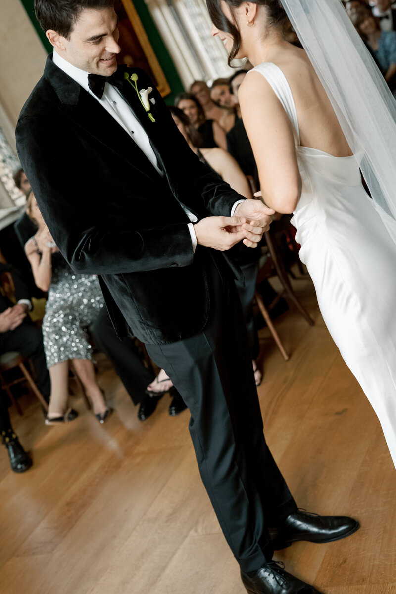 Groom slips ring onto bride’s finger during vows at The Charterhouse.